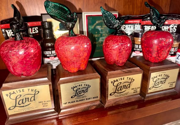 A row of red glass-apple Praise the Lard trophies